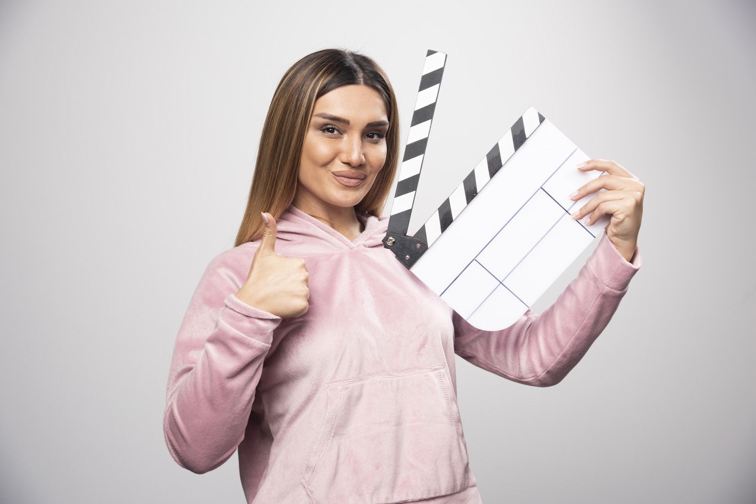 blond-lady-pink-sweatshirt-holding-blank-clapper-board-gives-professional-poses (1).jpg